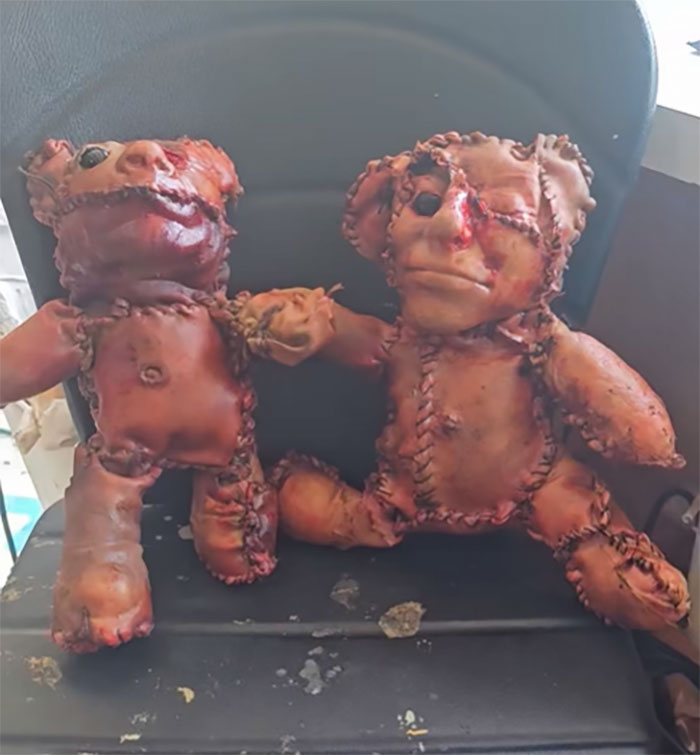 Two horrifying teddy bears covered in apparent human remains sitting on a black chair with stitched details Two horrifying teddy bears covered in apparent human remains sitting on a black chair with stitched details