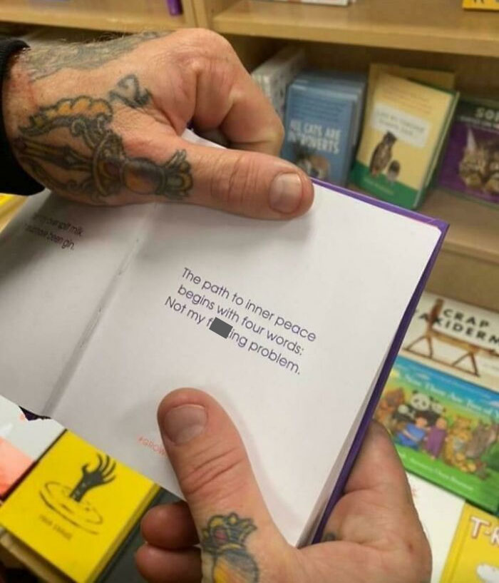 Hands with tattoos holding a small book with a quote about inner peace showing suspiciously unbothered attitude.