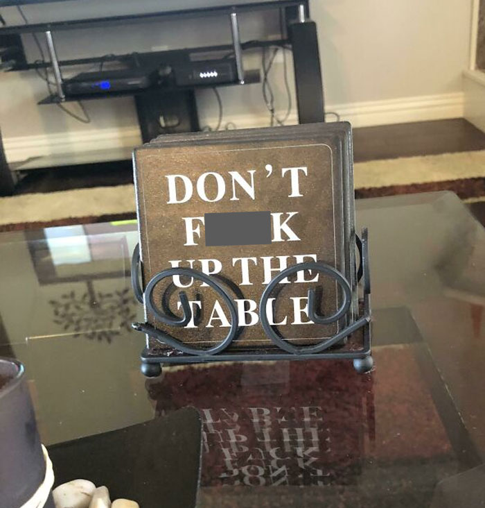 Coasters on glass table with a bold message, showing suspiciously unbothered attitude toward the world around them.