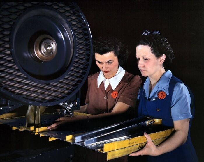 Two women at work during WWII operating industrial machinery in a factory, showcasing women at work during WWII.