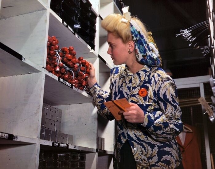 Woman at work during WWII examining organized supplies in a factory setting, representing women at work during WWII.