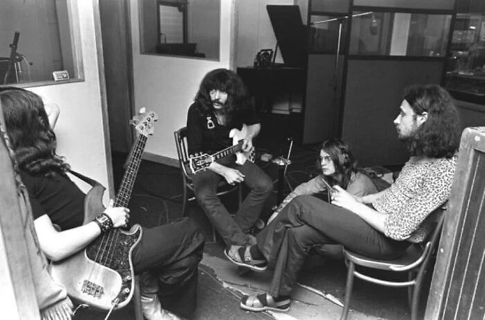 1970s rock legends in studio session with instruments, discussing music creation during their greatest recording phase.