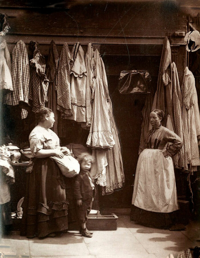 Two women and a child in a small overcrowded living space showing how London's poorest really lived in the 1800s.