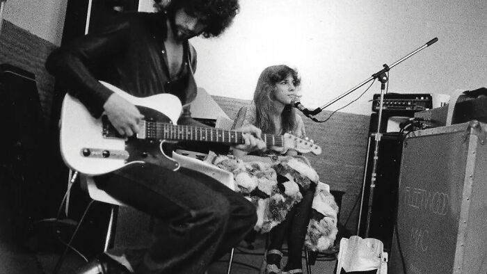 1970s rock legends in a raw studio session, with a guitarist and singer creating iconic music in an intimate setting