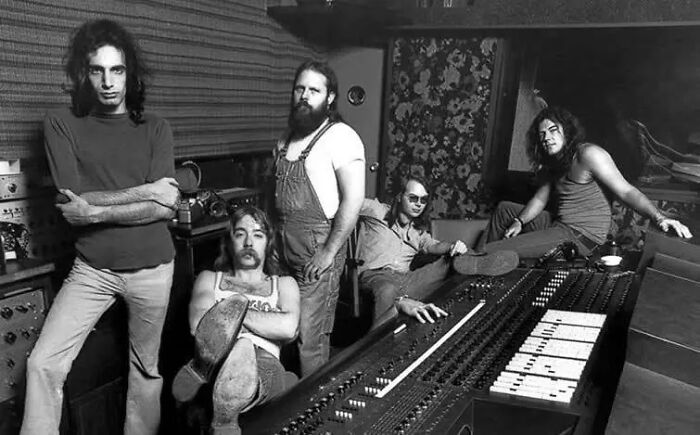 1970s rock legends in a recording studio surrounded by audio equipment, creating their greatest music in a raw session.