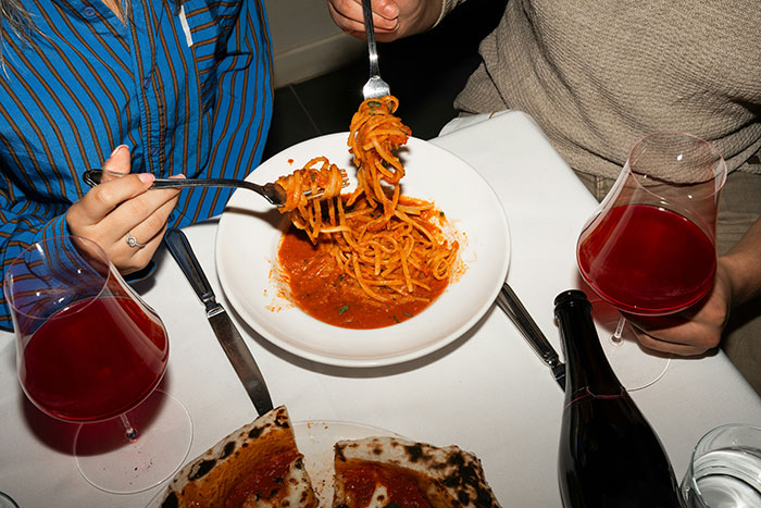 Couple eating pasta and pizza with red wine on table, highlighting inlaws day ruined genetic heritage tension. Couple eating pasta and pizza with red wine on table, highlighting inlaws day ruined genetic heritage tension.