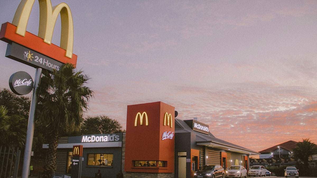 McDonald's restaurant exterior at dusk with cars parked, highlighting McDonald's employees and bizarre experiences theme.