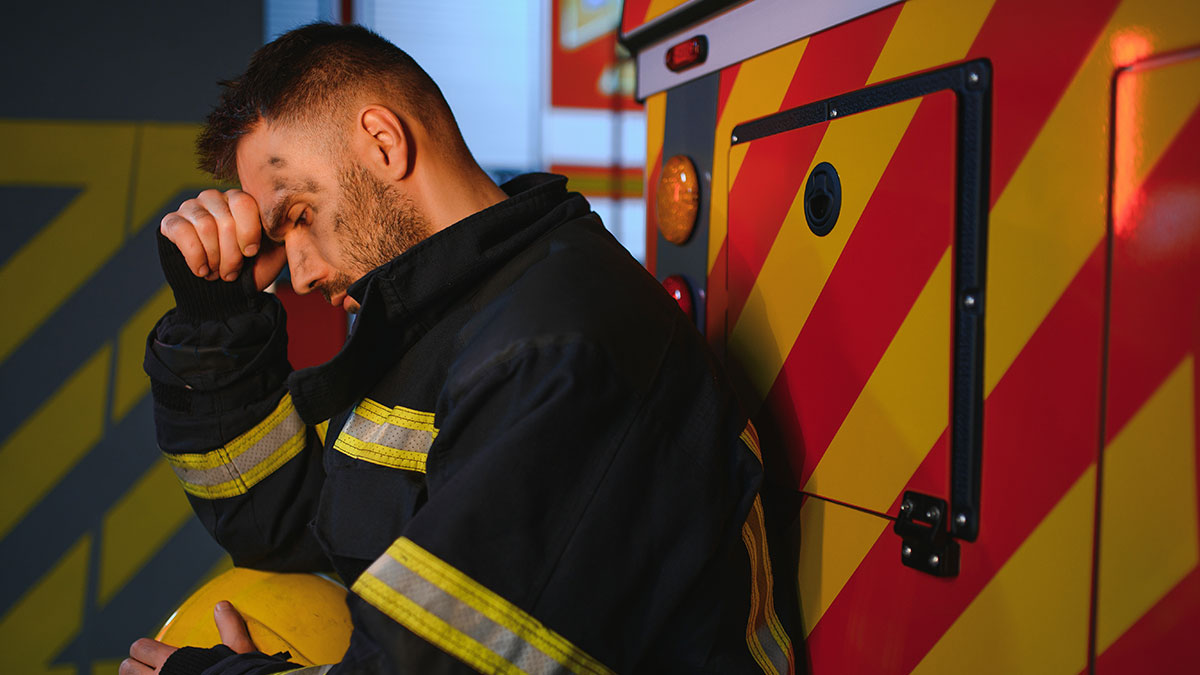 A firefighter in uniform sitting by a fire truck looking distressed, evoking creepy true stories that haunt people.