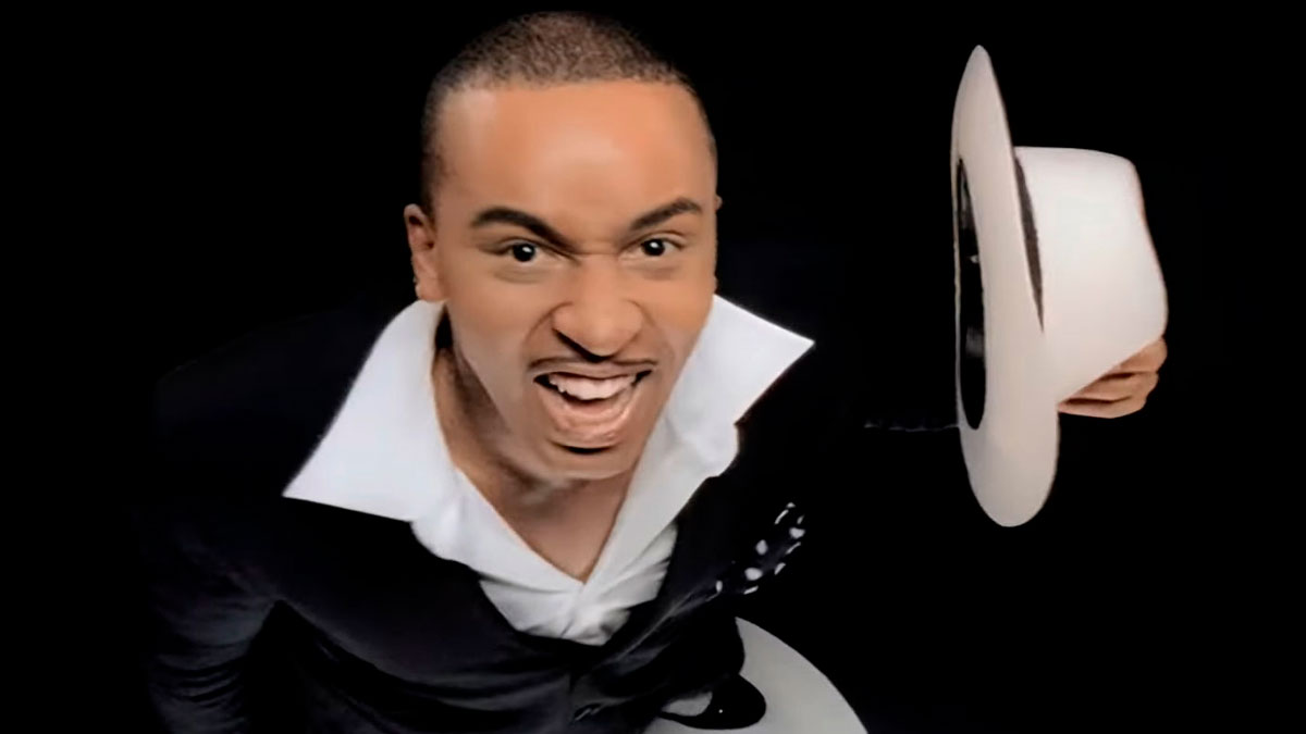 Man in a black suit and white shirt holding a white hat, expressing excitement related to Singapore mass panic event.