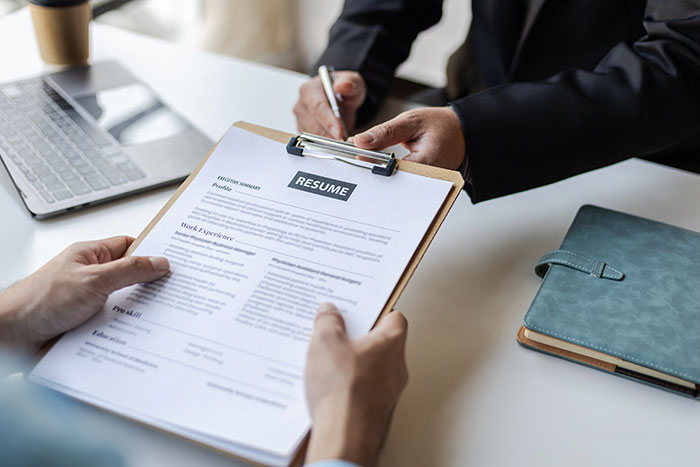 Job interview scene with a candidate holding a resume and an interviewer taking notes before hiring decision. Job interview scene with a candidate holding a resume and an interviewer taking notes before hiring decision.