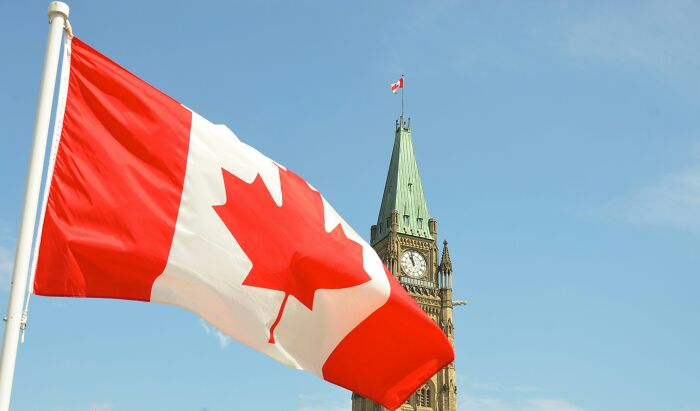 Canadian flag waving in front of a historic clock tower, representing one of the smartest countries shaping the future.