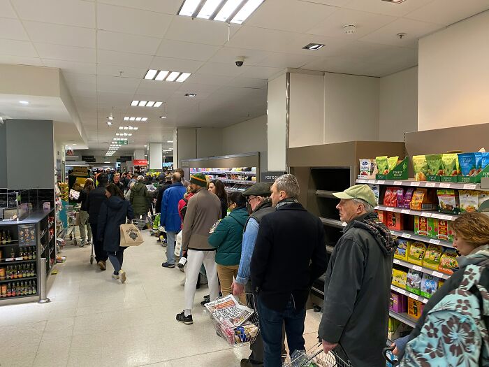 Shoppers standing in a crowded supermarket aisle, demonstrating unusual public behavior in everyday settings.