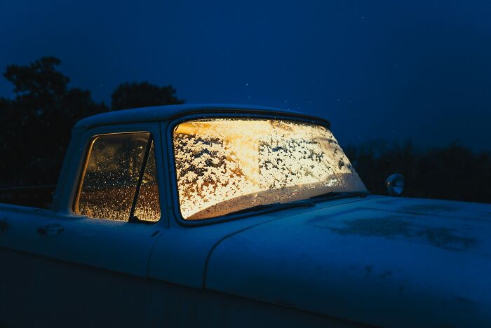 Old pickup truck covered in frost at night with warm light glowing through the icy windshield, illustrating debunked lies people believe.