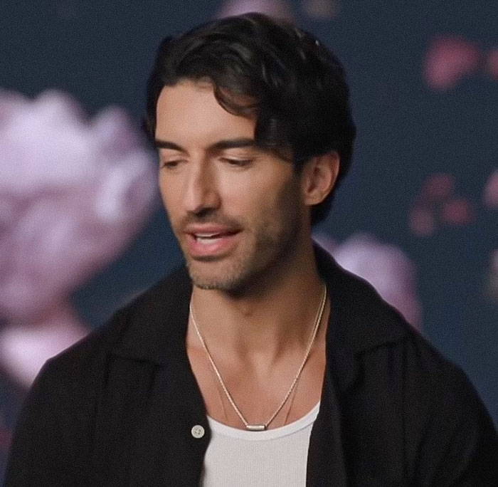 Man with dark hair wearing layered necklaces and a black shirt in a studio setting discussing Blake Lively court reality check Man with dark hair wearing layered necklaces and a black shirt in a studio setting discussing Blake Lively court reality check