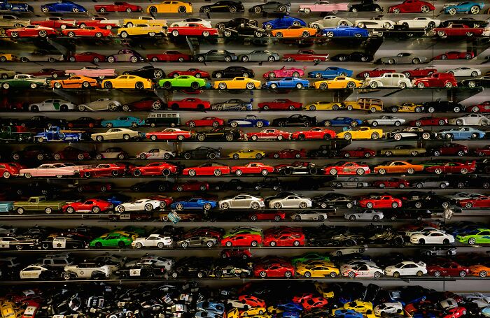 Collection of colorful toy cars displayed on shelves representing trends contributing to overconsumption in society.