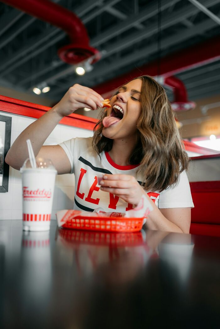 Woman enjoying food at a diner, demonstrating calm communication skills in a relaxed and casual setting.