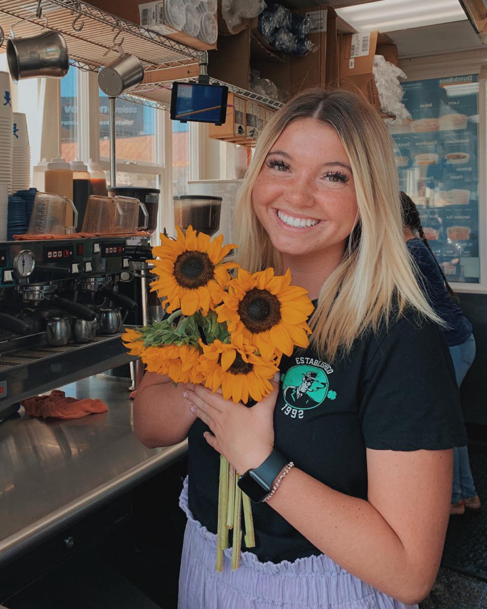 Young woman holding sunflowers indoors, related to mother of Bryan Kohberger's victim sharing details about violent massacre. Young woman holding sunflowers indoors, related to mother of Bryan Kohberger's victim sharing details about violent massacre.
