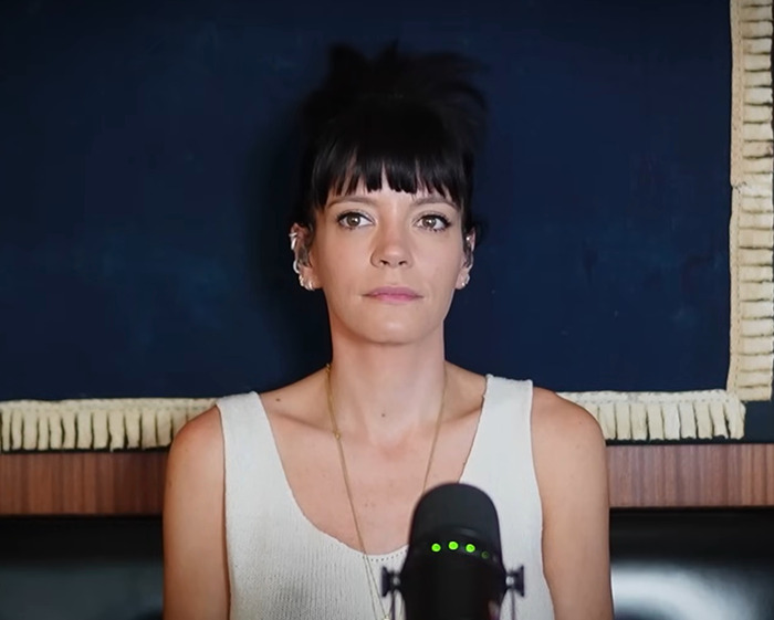 Lily Allen speaking into a microphone with a neutral expression, highlighting her abortion confession controversy. Lily Allen speaking into a microphone with a neutral expression, highlighting her abortion confession controversy.