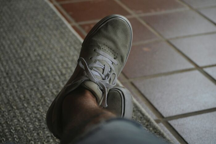 Close-up of casual shoes resting on floor tiles, representing McDonald's employees sharing bizarre experiences.