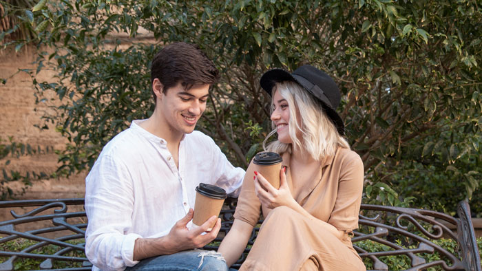 Teen holding coffee with woman on bench outdoors, reflecting struggle of teen losing parents and working two jobs. Teen holding coffee with woman on bench outdoors, reflecting struggle of teen losing parents and working two jobs.