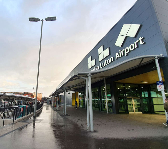 London Luton Airport exterior with wet pavement, relating to man threatening to explode plane mid-flight incident. London Luton Airport exterior with wet pavement, relating to man threatening to explode plane mid-flight incident.