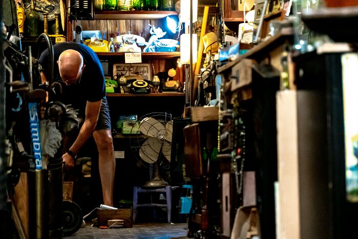 Man in a cluttered vintage shop, bending down, surrounded by antiques and old objects, people share reasons not divorced