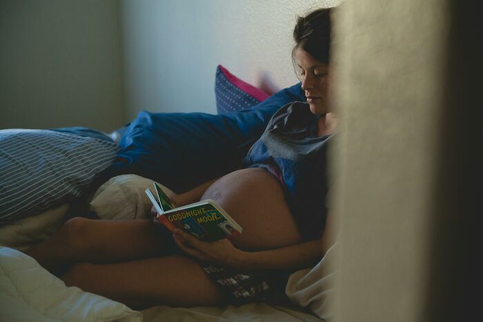 Pregnant woman reading a book in bed, highlighting tension with guy fed up with pregnant roomie situation. Pregnant woman reading a book in bed, highlighting tension with guy fed up with pregnant roomie situation.