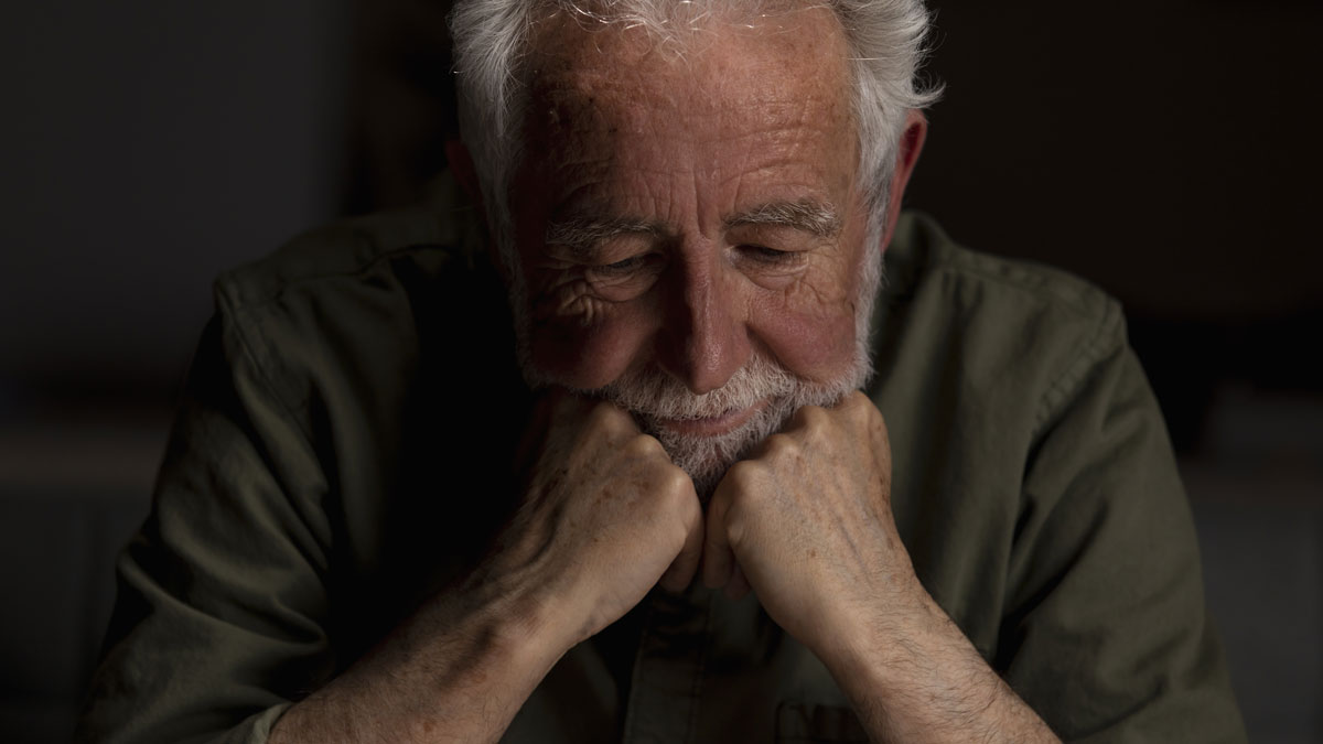 Elderly man in deep thought, resting his chin on his fists, reflecting on ex-dil kids vacation home issues.