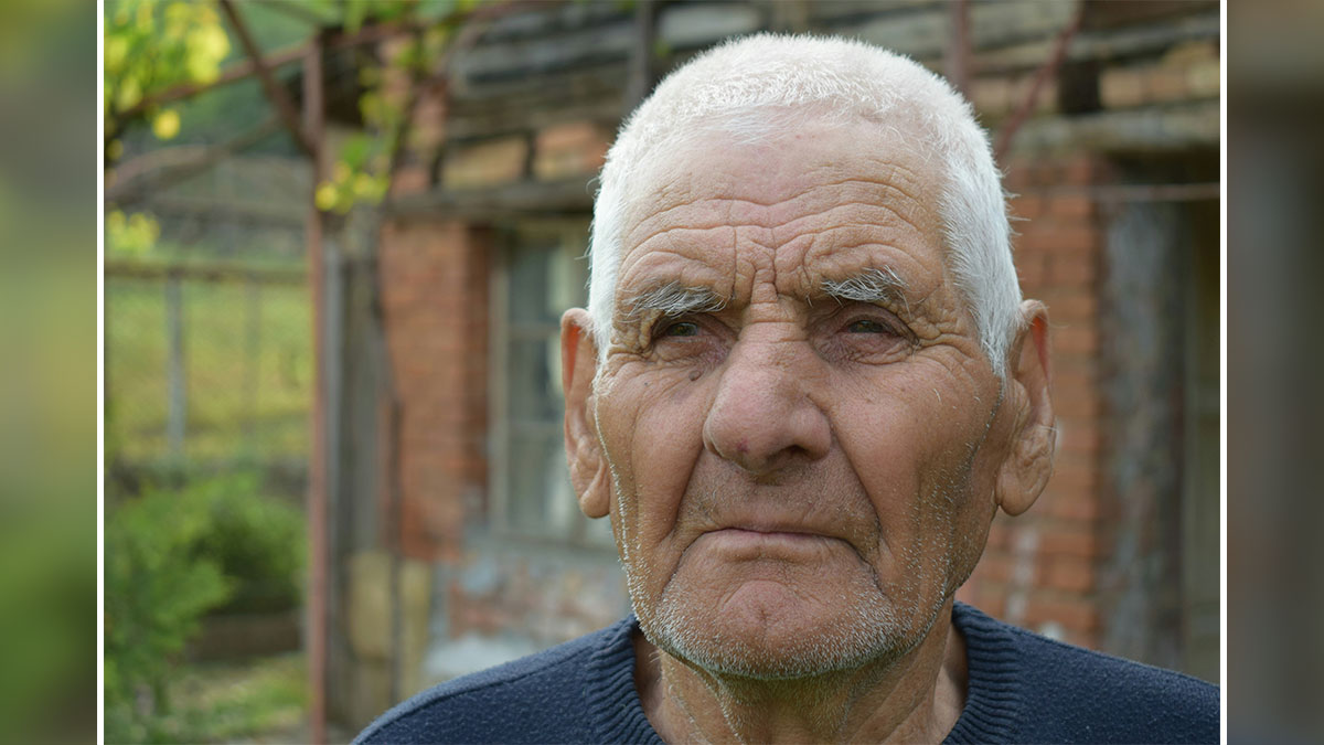 Elderly quiet retiree standing outside a rustic home, reflecting a shocking neighbor story about leaving apartment after passing.