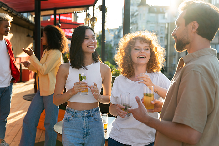 Group of young adults socializing outdoors with drinks, capturing a playful flirty bachelor vibe after public demotion to friend. Group of young adults socializing outdoors with drinks, capturing a playful flirty bachelor vibe after public demotion to friend.