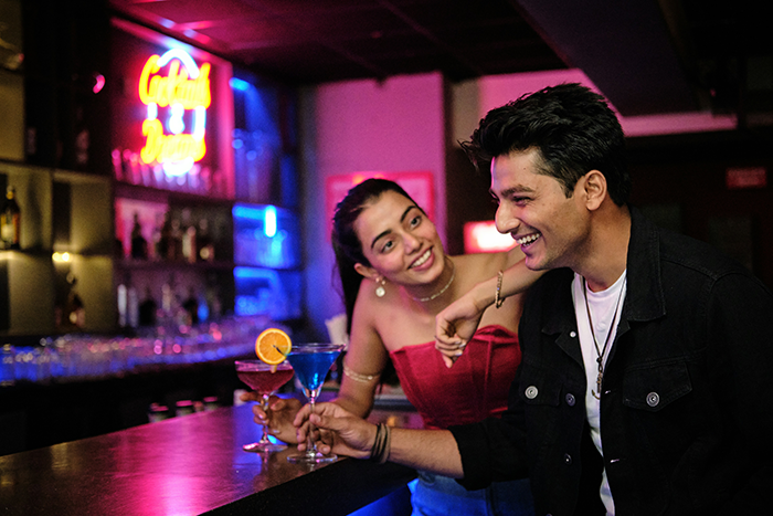 Man flirting with woman at a bar, enjoying drinks and lively conversation in a social nightlife setting. Man flirting with woman at a bar, enjoying drinks and lively conversation in a social nightlife setting.