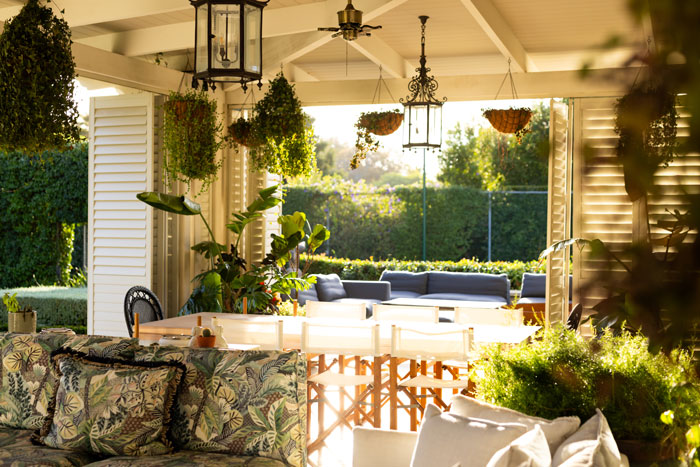 Man relaxing on a patio surrounded by lush plants and cozy seating in a bright, sunlit outdoor space. Man relaxing on a patio surrounded by lush plants and cozy seating in a bright, sunlit outdoor space.