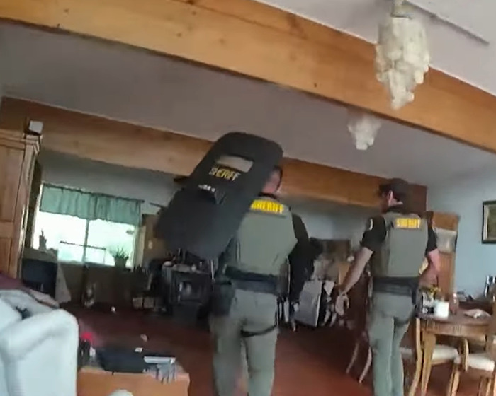 Two sheriff officers inside a home investigating the horrifying scene of a family slaying incident. Two sheriff officers inside a home investigating the horrifying scene of a family slaying incident.