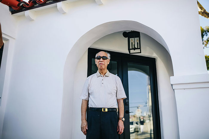 Elderly man standing outside house with black door, representing father and son lock horns over changing locks conflict. Elderly man standing outside house with black door, representing father and son lock horns over changing locks conflict.
