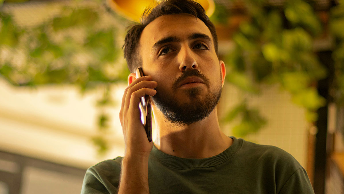 Young man with beard making a serious phone call amid father and son lock horns house lock dispute