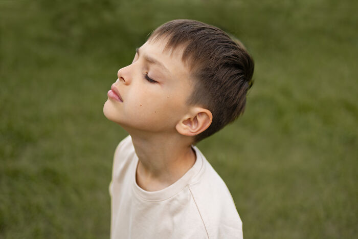 Young boy outdoors with eyes closed, reflecting on advice kids were given that was manipulation in disguise.
