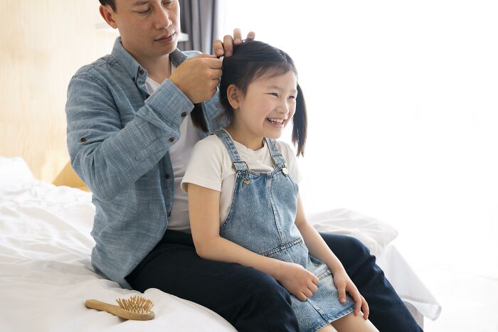 Father fixing daughter’s hair while sitting on bed, illustrating advice kids were given that later revealed manipulation.
