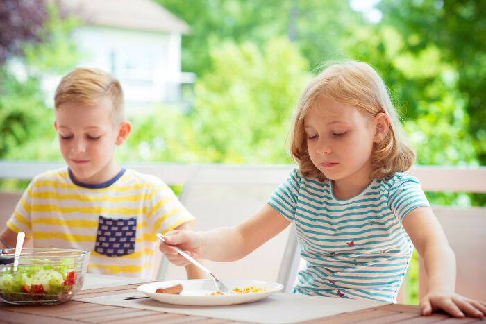 Two kids sitting at a table outdoors, having food, illustrating advice kids were given that was manipulation in disguise.
