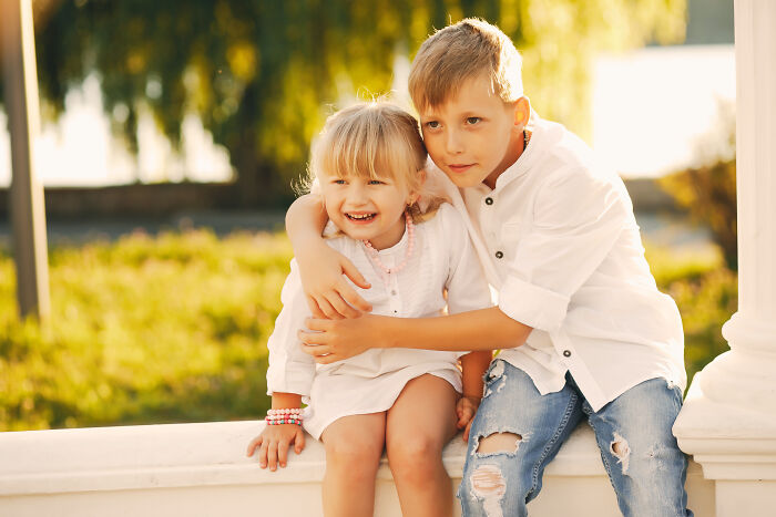 Two kids sitting outdoors, a boy and girl hugging, representing advice kids received and manipulation themes.