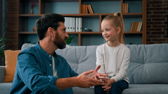 Man talking to a smiling child on a couch, illustrating advice kids were given that was manipulation in disguise.