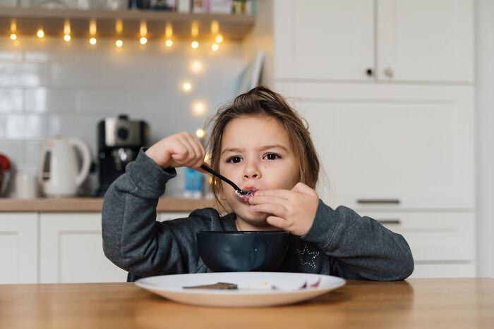 Young child eating from a bowl at the kitchen table, reflecting on advice kids were given that hides manipulation.