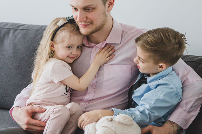 Father sitting on couch with two kids, showing love and connection in marriage and relationship with children. Father sitting on couch with two kids, showing love and connection in marriage and relationship with children.