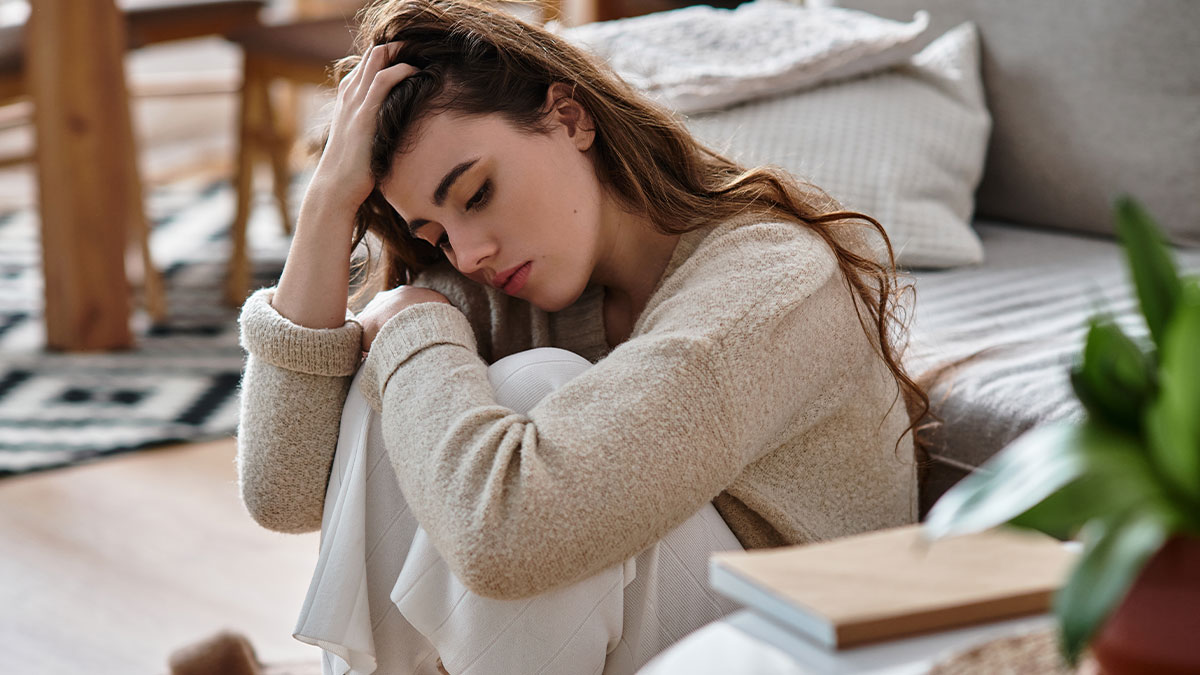Sad woman sitting on the floor, looking distressed, reflecting the conflict about having kids and stepkids issues.