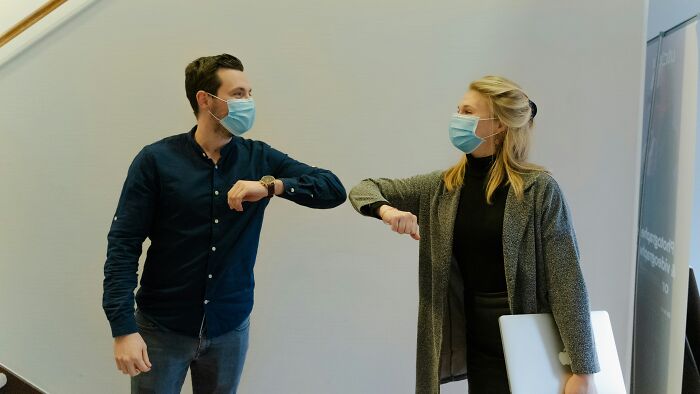 Two people wearing masks greeting with elbow bumps, illustrating bizarre beliefs people still fall for despite science.