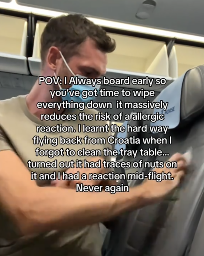 Passenger on a flight wearing a mask, wiping down seat surfaces to reduce allergy risks before takeoff. Passenger on a flight wearing a mask, wiping down seat surfaces to reduce allergy risks before takeoff.