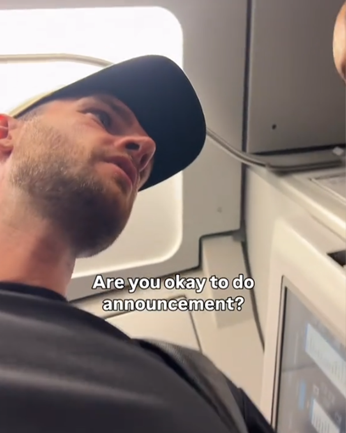 Man wearing a black cap inside an airplane cabin preparing to make a passenger's allergy request announcement on a flight. Man wearing a black cap inside an airplane cabin preparing to make a passenger's allergy request announcement on a flight.