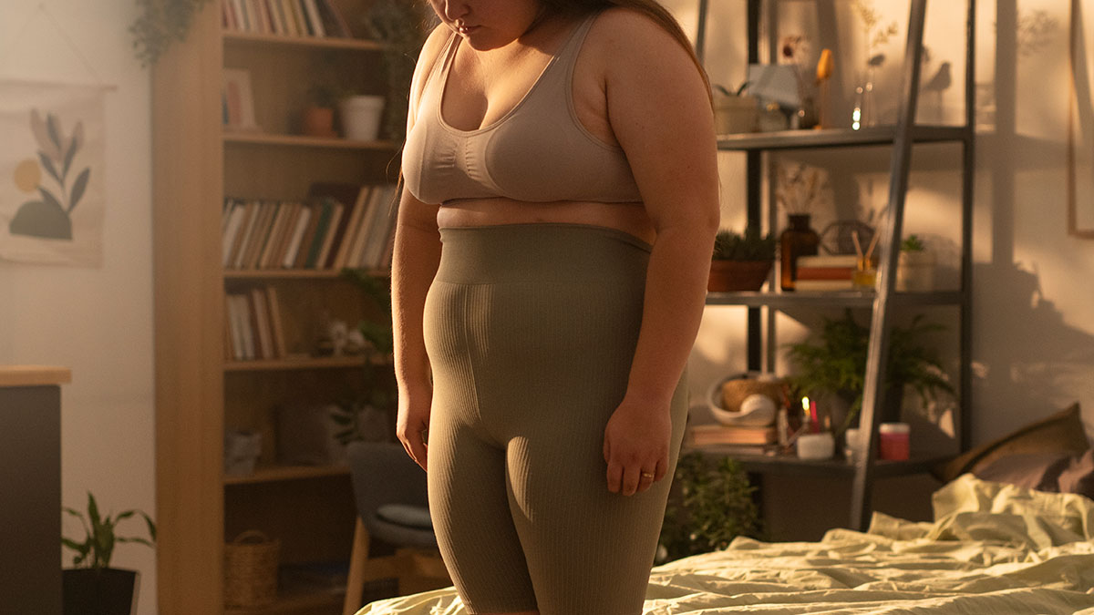 Woman standing in bedroom looking down, illustrating the impact of being gaslit by a doctor in a personal experience context.