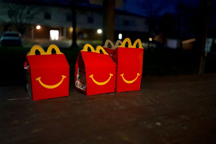 McDonald's Happy Meal boxes lined up on a wooden surface at night, reflecting employees' bizarre experiences.