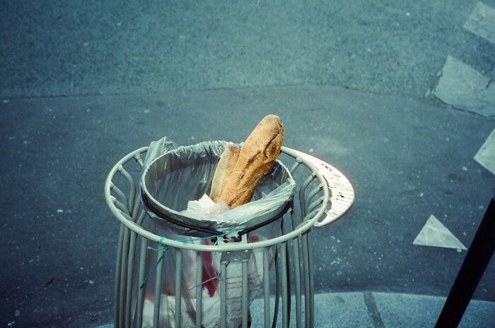 Loaf of bread discarded in a trash can, highlighting the global food waste crisis and its economic impact.