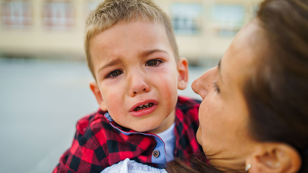 Woman caregiver comforting crying child outdoors after allergy incidents, facing family backlash and legal threats.